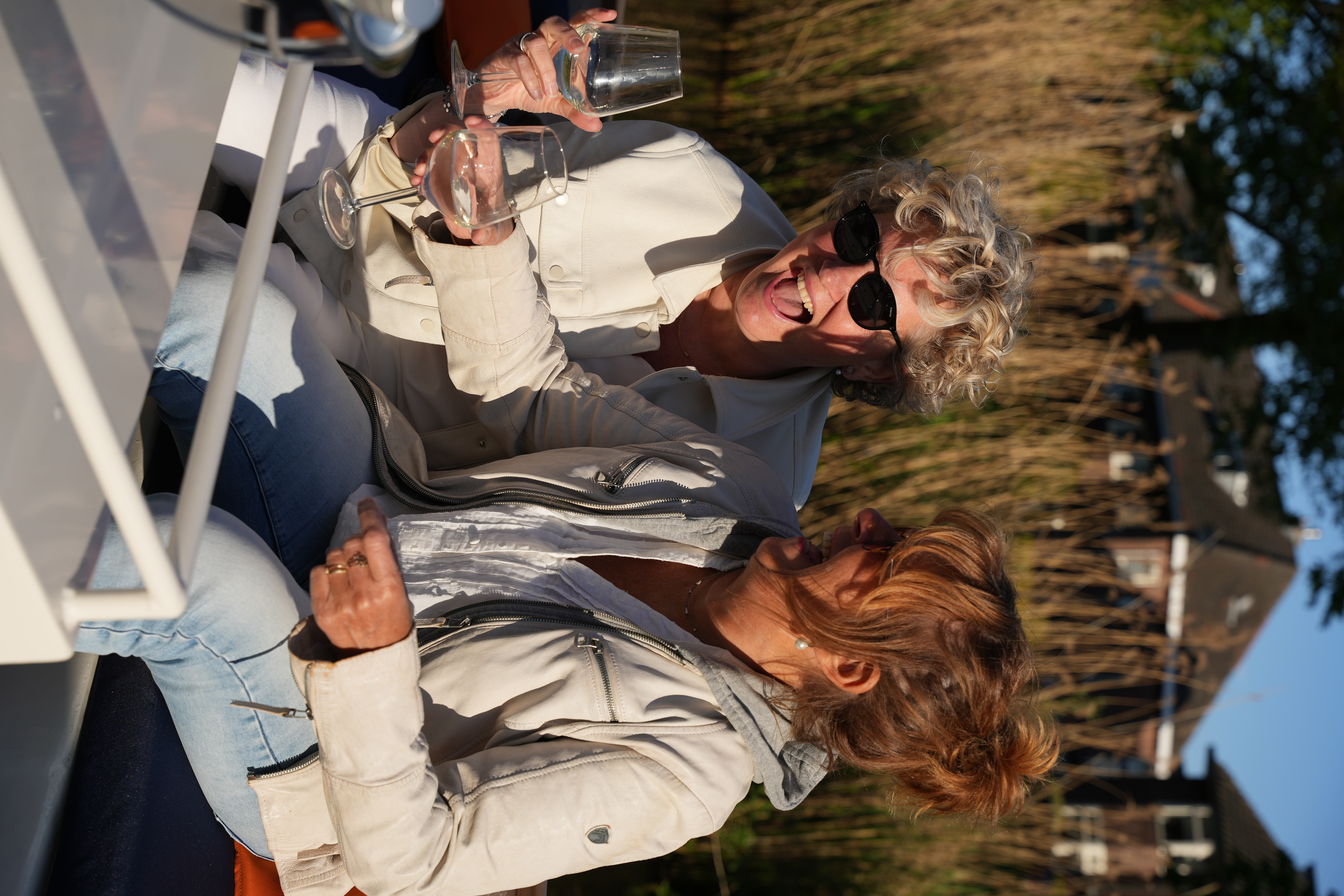 Rondvaart in Breda met Ervaar Breda op de borrelboot over de singels van Breda, waar gasten lachen en wijn drinken aan boord.